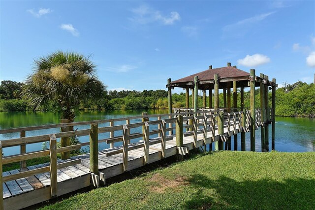 view of dock with a lawn and a water view