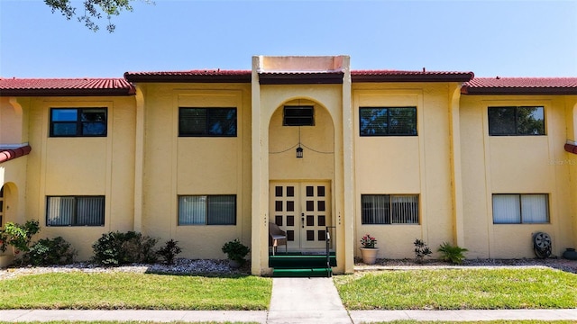 view of property featuring french doors, a tiled roof, and stucco siding