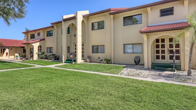 exterior space featuring stucco siding, a tile roof, and a lawn