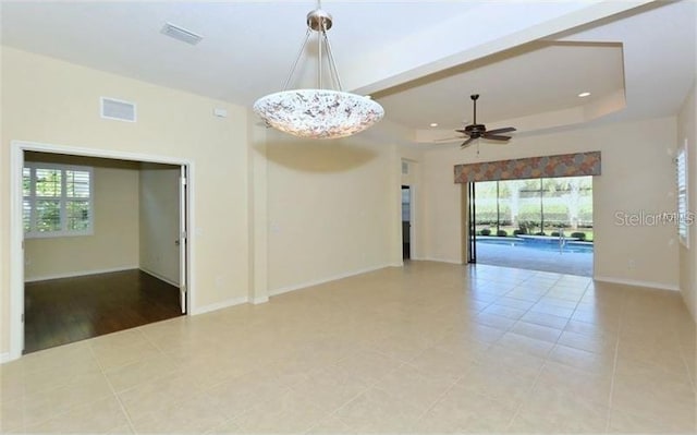 unfurnished room featuring visible vents, a wealth of natural light, a raised ceiling, and ceiling fan with notable chandelier