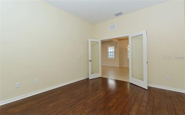 unfurnished room with french doors, hardwood / wood-style floors, visible vents, and baseboards