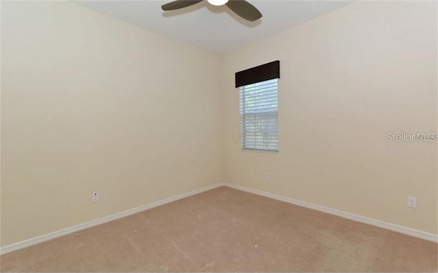 spare room featuring ceiling fan, light colored carpet, and baseboards