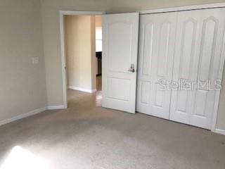 unfurnished bedroom with baseboards, a closet, and carpet