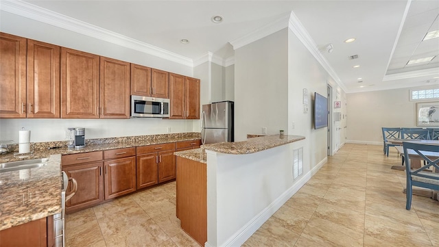 kitchen with light stone countertops, brown cabinetry, appliances with stainless steel finishes, ornamental molding, and a peninsula