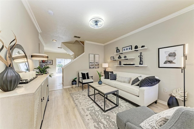 living area featuring baseboards, visible vents, light wood-type flooring, and ornamental molding