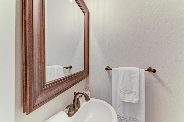 half bathroom featuring a sink and a textured wall