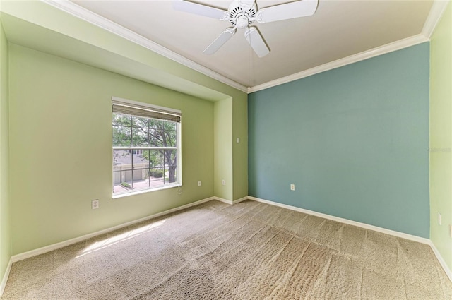 carpeted spare room featuring crown molding, baseboards, and a ceiling fan