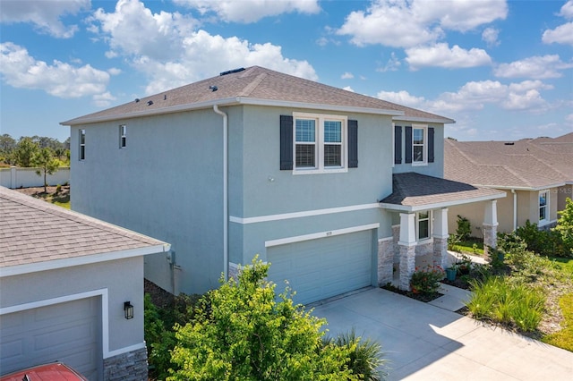 view of property exterior with an attached garage, stone siding, and stucco siding