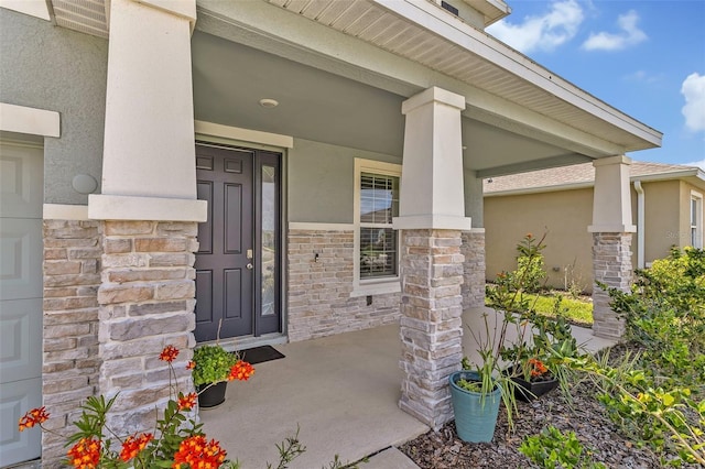 entrance to property with covered porch, stucco siding, and stone siding