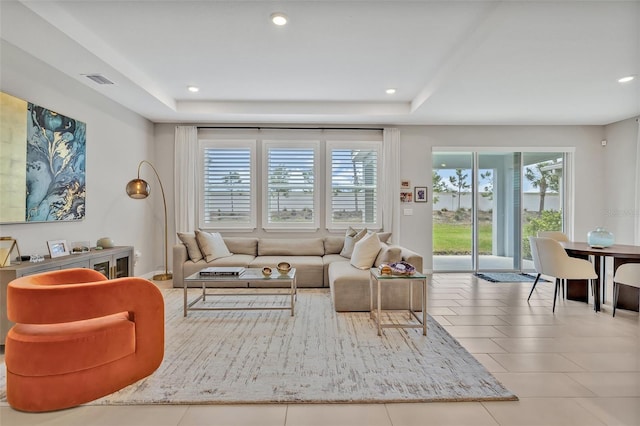 tiled living room with a tray ceiling, visible vents, and recessed lighting