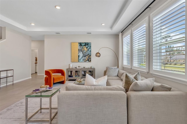 living area with a tray ceiling, baseboards, and recessed lighting