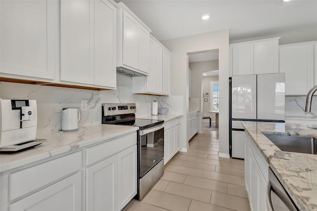 kitchen featuring white cabinets, a sink, appliances with stainless steel finishes, backsplash, and light stone counters