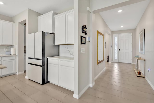 kitchen with white cabinets, light countertops, and freestanding refrigerator