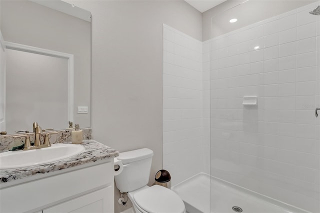 bathroom featuring toilet, vanity, and a tile shower