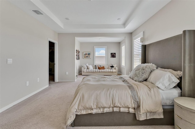 bedroom with visible vents, baseboards, a tray ceiling, and light colored carpet