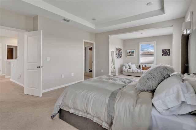 bedroom with visible vents, a tray ceiling, baseboards, and light carpet
