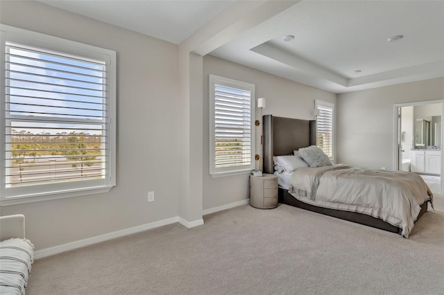 carpeted bedroom featuring a tray ceiling, baseboards, and connected bathroom