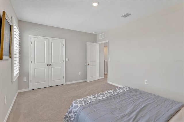 carpeted bedroom with a closet, baseboards, and visible vents