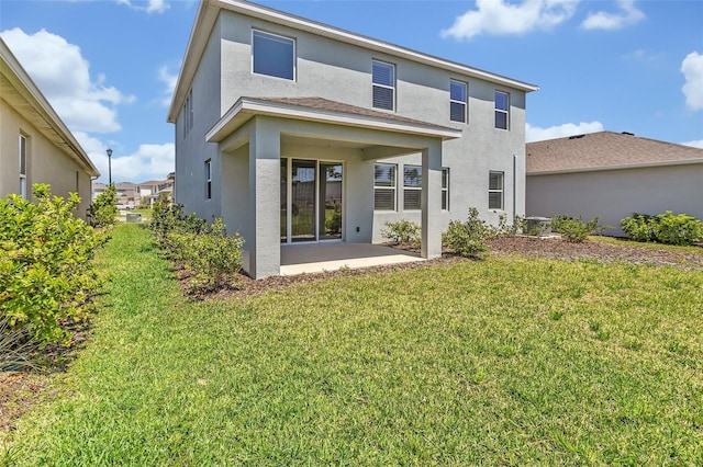 rear view of property with a patio, stucco siding, and a lawn