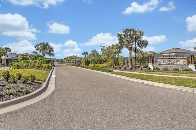view of street featuring street lights, curbs, a gated entry, a gate, and sidewalks