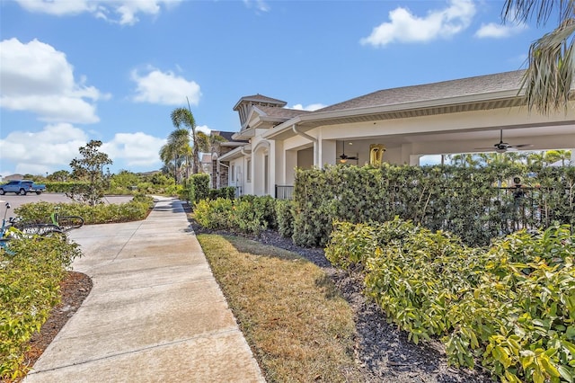 view of side of property featuring stucco siding and a ceiling fan