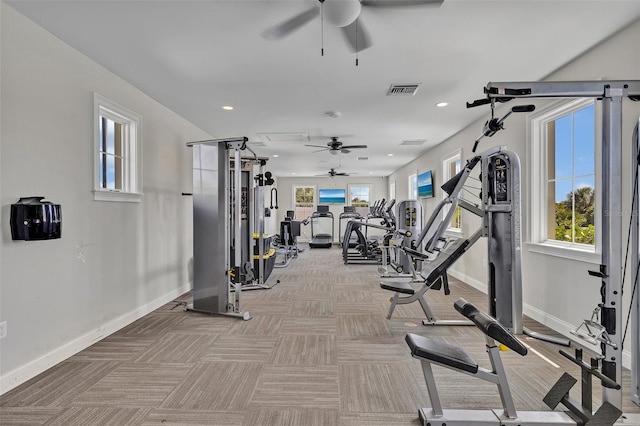 gym featuring light carpet, a wealth of natural light, baseboards, and a ceiling fan