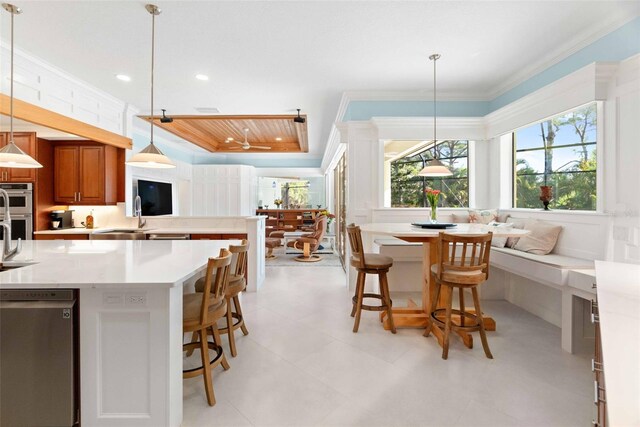 2196 Muskogee Trl, Nokomis, FL 34275 - kitchen featuring brown cabinetry, ornamental molding, light countertops, a kitchen breakfast bar, and double oven