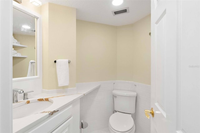 2196 Muskogee Trl, Nokomis, FL 34275 - bathroom featuring a wainscoted wall, toilet, vanity, and tile walls