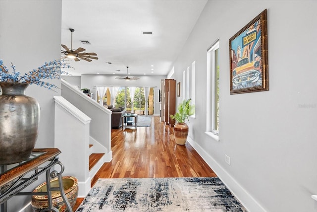 hall featuring stairs, visible vents, light wood-type flooring, and baseboards