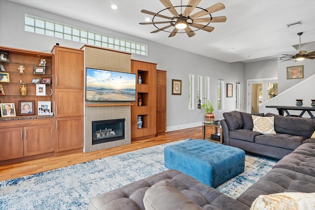 living room featuring light wood-style flooring, a ceiling fan, visible vents, and plenty of natural light