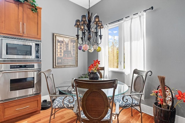 dining space with light wood finished floors, a notable chandelier, and baseboards