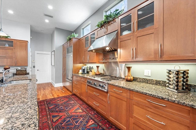 kitchen with under cabinet range hood, visible vents, brown cabinetry, stainless steel appliances, and a sink