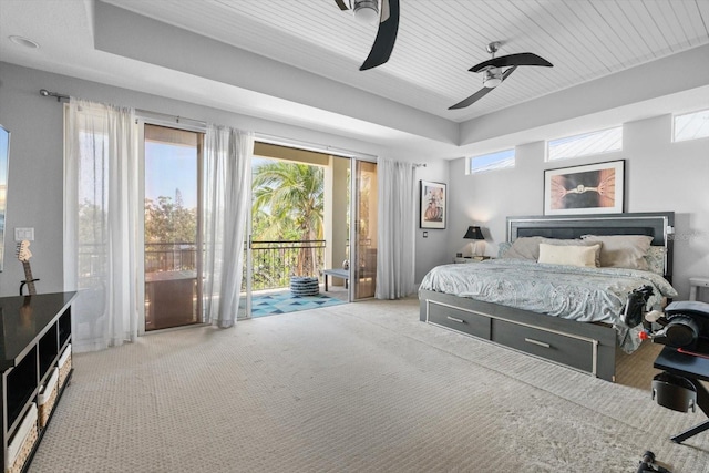 carpeted bedroom with a tray ceiling, access to outside, and a ceiling fan