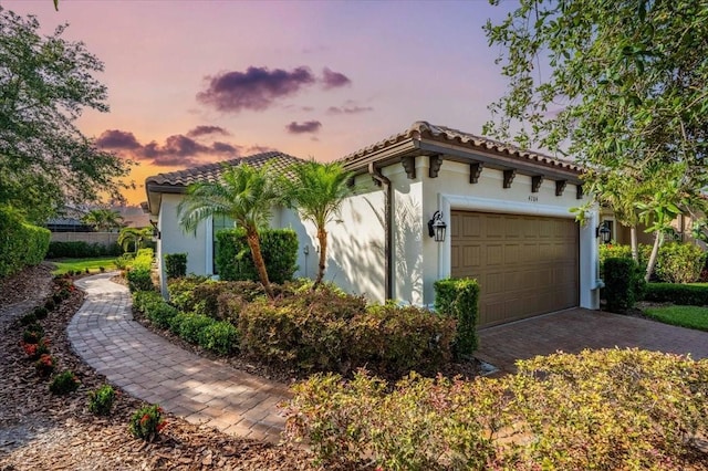 4704 Stafford Ct, Palmetto, FL 34221 - property exterior at dusk with stucco siding, a garage, a tile roof, and driveway
