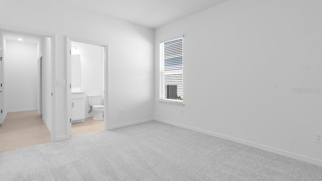 1599 Laurel Brook Ln, Port Charlotte, FL 33953 - unfurnished bedroom featuring light colored carpet, baseboards, connected bathroom, and light tile patterned floors