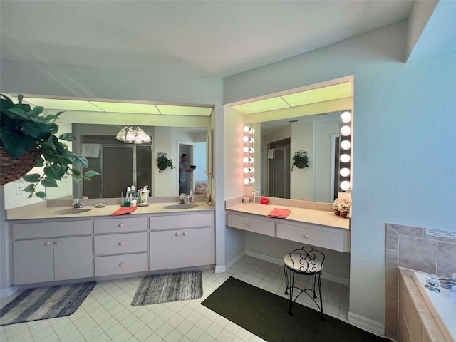 full bathroom featuring double vanity, a sink, tiled tub, and tile patterned flooring