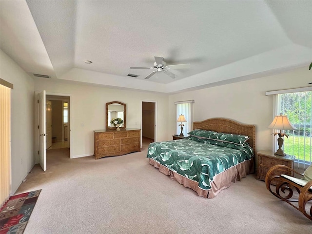 carpeted bedroom featuring a tray ceiling, visible vents, a ceiling fan, and a textured ceiling