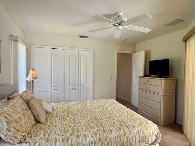 bedroom with a closet, a ceiling fan, visible vents, and carpet