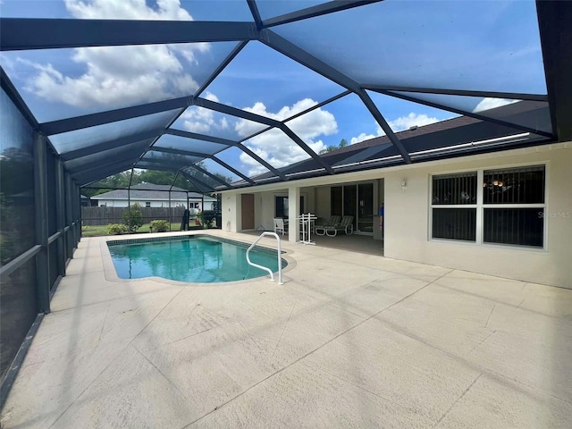 pool featuring glass enclosure, fence, and a patio area