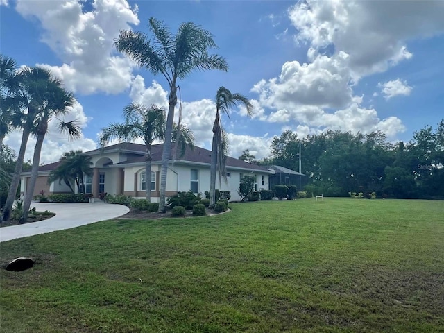 view of front facade with a front yard, stucco siding, and curved driveway