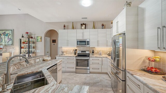 1085 Mallard Marsh Dr, Osprey, FL 34229 - kitchen featuring arched walkways, a sink, visible vents, decorative backsplash, and appliances with stainless steel finishes