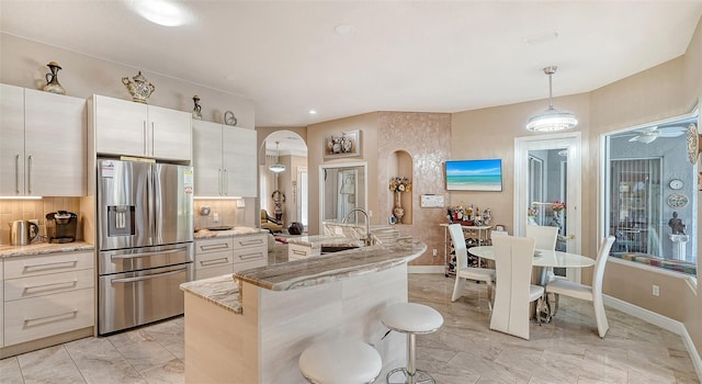 1085 Mallard Marsh Dr, Osprey, FL 34229 - kitchen with arched walkways, a sink, tasteful backsplash, marble finish floor, and stainless steel refrigerator with ice dispenser