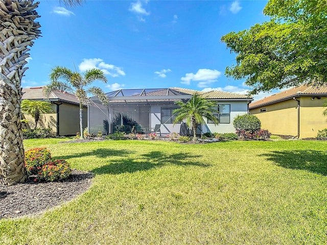 13724 Quinta St, Venice, FL 34293 - rear view of house featuring a tile roof, stucco siding, glass enclosure, and a lawn