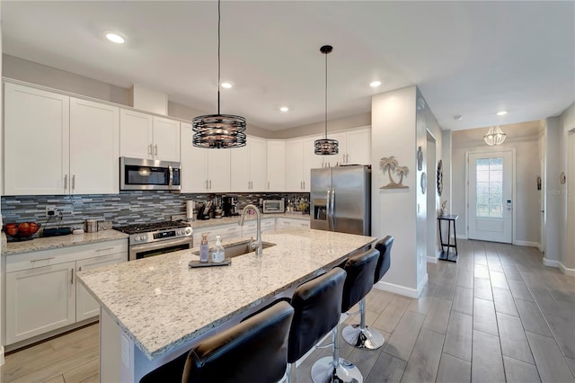15719 Barefoot Beach Dr, Lakewood Ranch, FL 34211 - kitchen with stainless steel appliances, decorative backsplash, a kitchen breakfast bar, white cabinetry, and recessed lighting