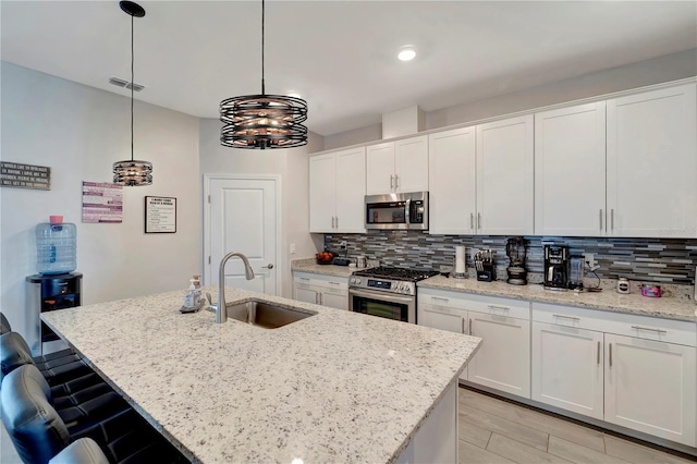 15719 Barefoot Beach Dr, Lakewood Ranch, FL 34211 - kitchen featuring appliances with stainless steel finishes, tasteful backsplash, white cabinets, and a kitchen island with sink