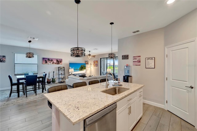 15719 Barefoot Beach Dr, Lakewood Ranch, FL 34211 - kitchen featuring dishwasher, light wood-style flooring, white cabinets, hanging light fixtures, and a center island with sink