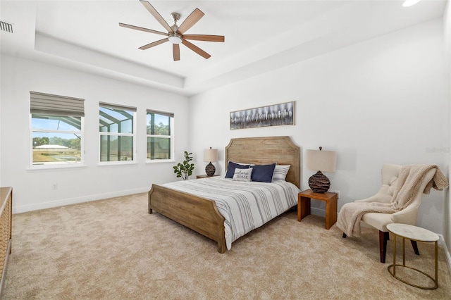 4712 Margutta Ct, Sarasota, FL 34240 - bedroom featuring light carpet, baseboards, a tray ceiling, and a ceiling fan