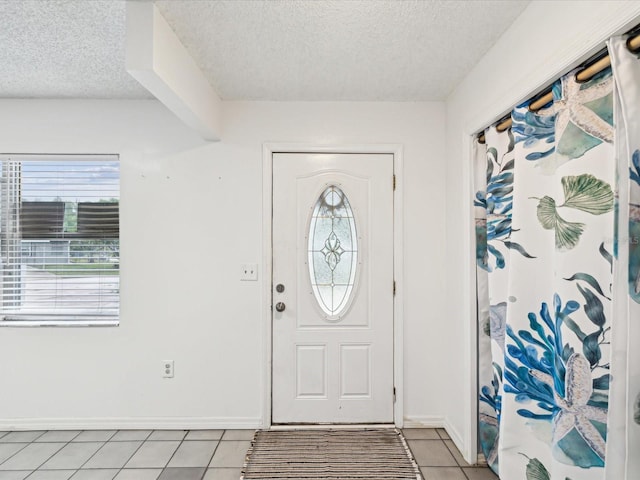 entryway featuring a textured ceiling, light tile patterned floors, and baseboards