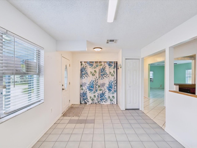 foyer entrance with light tile patterned floors, visible vents, and a textured ceiling