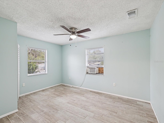 spare room with wood finished floors, a ceiling fan, visible vents, and plenty of natural light